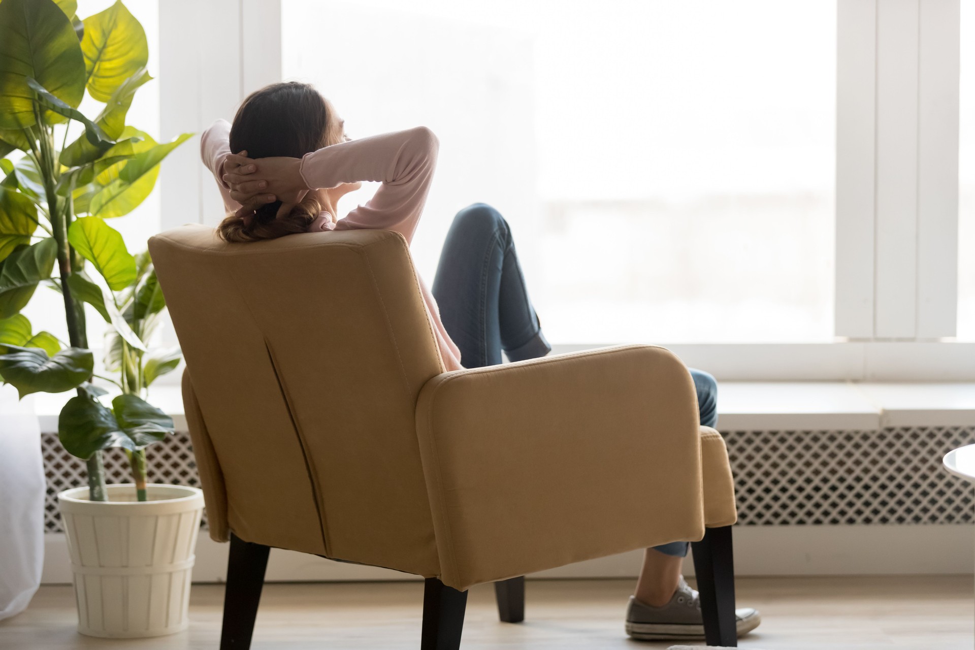 Young woman resting in comfortable armchair back view.